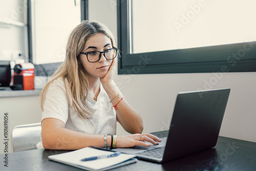 Happy young blonde business woman entrepreneur using computer looking at screen working in internet sit at office desk, smiling millennial female professional employee typing email on laptop workplace