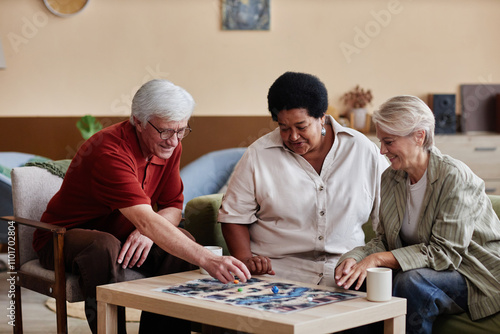 Group of elegant senior people playing board game together enjoying quiet entertainment indoors in cozy living room photo