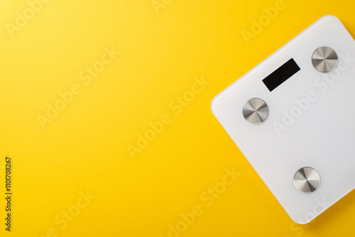 A sleek digital bathroom scale placed on a bright yellow surface, symbolizing health and fitness concepts with a minimalist design photo