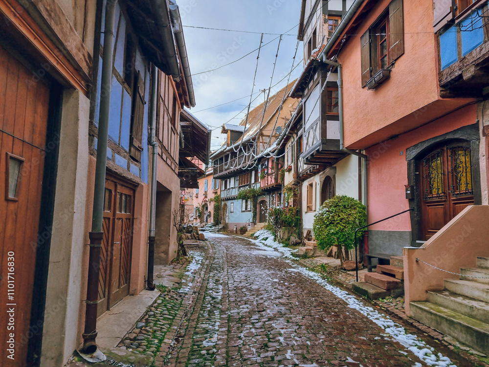 Obraz premium Eguisheim with Christmas decoration - Charming, colorful, snowy cobblestone street with half-timbered houses in snow and colorful facades, France's most beautiful village, Alsace region, France