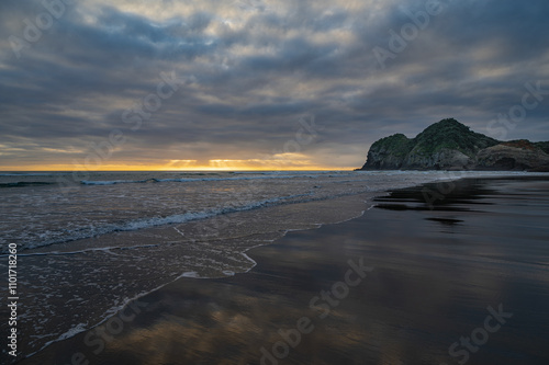 Beautiful sunset moment at the reflective Bethells surf beach, Auckland, New Zealand