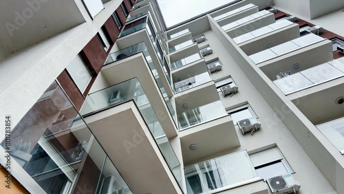 Photo of Low-Angle View of a Modern Apartment Building with Glass Balconies and Air Conditioners