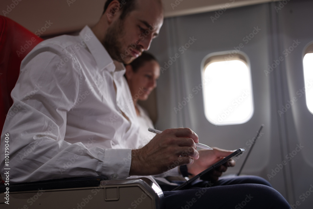 Business Professionals Using Digital Devices on Airplane Seats During Flight, Working on Laptops and Tablets, Productivity and Comfort While Traveling, Focused on Tasks During Air Journey Business Professionals Using Digital Devices on Airplane Seats During Flight, Working on Laptops and Tablets, Productivity and Comfort While Traveling, Focused on Tasks During Air Journey