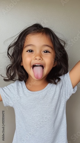 Happy child sticking out tongue while smiling at indoor setting in afternoon ...