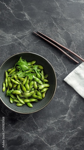 Fresh edamame in bowl with chopsticks on dark surface ready for a nutritious ...