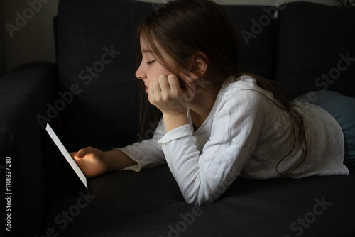 child with phone in his hands lying on sofa at home. kids gadgets