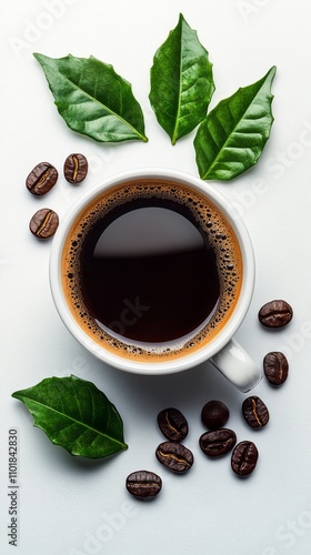 Freshly brewed coffee with coffee beans and green leaves arranged around a wh...