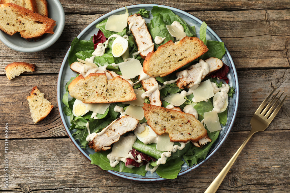Tasty Caesar salad with chicken served on wooden table, flat lay Tasty Caesar salad with chicken served on wooden table, flat lay