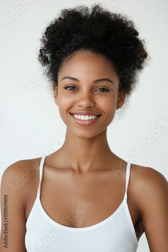 A woman with a white tank top and a black headband is smiling. She has a beautiful, natural look and a bright, happy expression