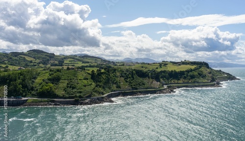 Scenic view of green mountains and the Cantabrian Sea on a bright sunny day in Getaria, Spain photo