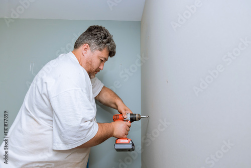 Contractor works diligently on home improvement task, using power drill to install plasterboard wall