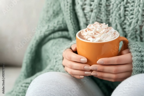 Cozy hands holding a warm cup of pumpkin spice latte topped with whipped cream