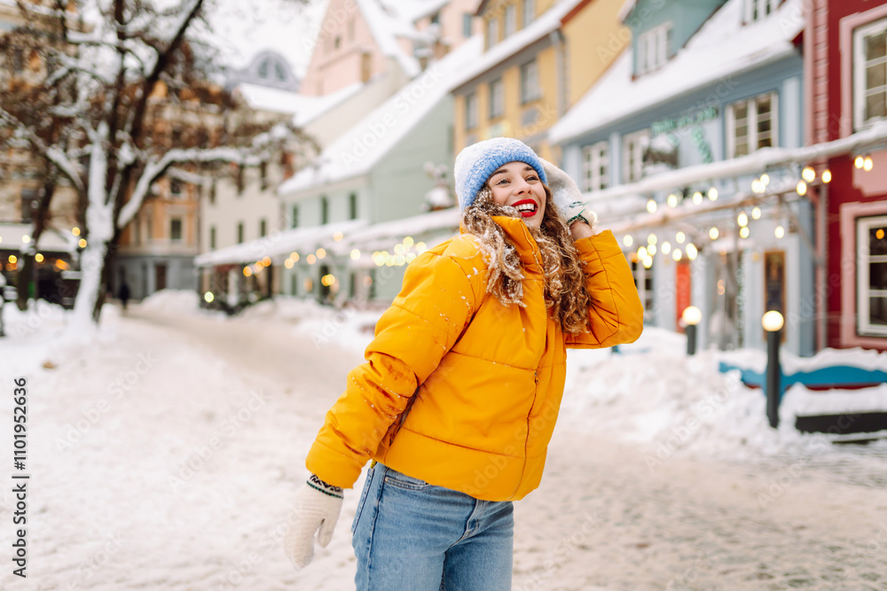 Fototapeta premium A young woman walks through street decorated with festive decorations and lights. Fashion style. Winter holidays.