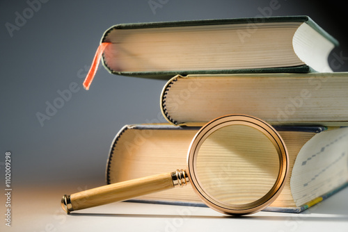 A magnifying glass with a pile of thick books, searching the information in the old books, glossary concept