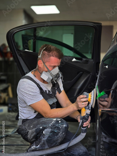 A skilled auto painter meticulously polishing a car to prepare it for painting, showcasing precision and craftsmanship in the workshop. photo