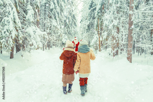 Foto Santa Claus with a bag of gifts and children in a snowy forest.