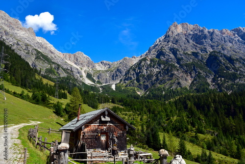 Gebirgspanorama mit hölzener Berghütte im Vordergrund