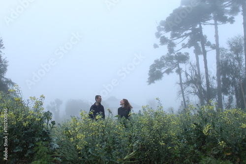 casal caminhando em meio a plantação com neblina ao fundo 