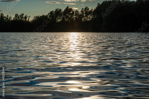 Serene Sunset Over the Calm Lake with Reflections of Trees and Clouds photo