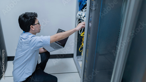 Computer engineer is setting up network in server room,Systems Maintenance Technician,Male engineer working in server room at modern data center