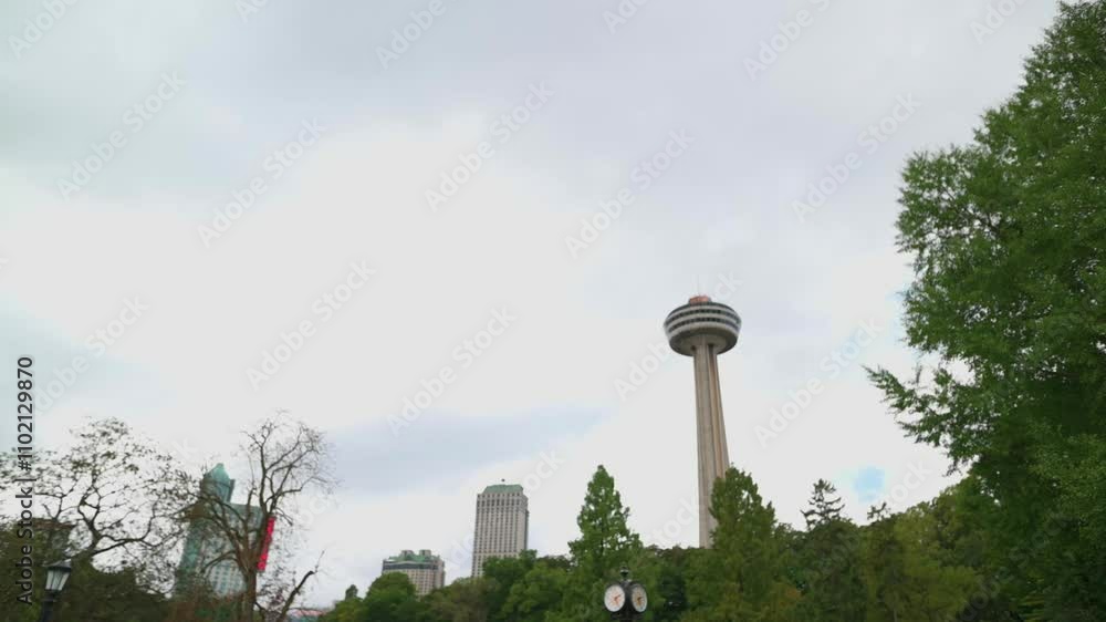 view of the Skylon Tower rising above trees and surrounding buildings under a cloudy sky, blending urban architecture with natural elements in Niagara Falls, Canada view of the Skylon Tower rising above trees and surrounding buildings under a cloudy sky, blending urban architecture with natural elements in Niagara Falls, Canada
