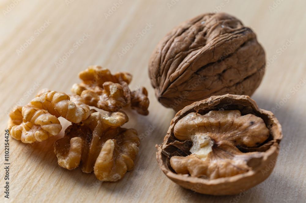 Shelled walnuts, kernels next to in-shell walnuts and nutcrackers. Production, consumption of walnuts, nutrition and properties of walnuts. Shelled walnuts, kernels next to in-shell walnuts and nutcrackers. Production, consumption of walnuts, nutrition and properties of walnuts.