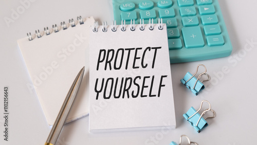 Protect yourself. Notepad with text on a white table. Near a calculator and paper clips.