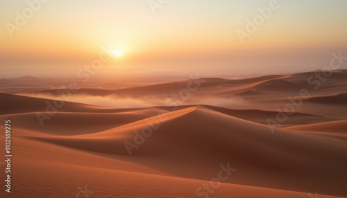 Sunrise over misty desert landscape with sand dunes.