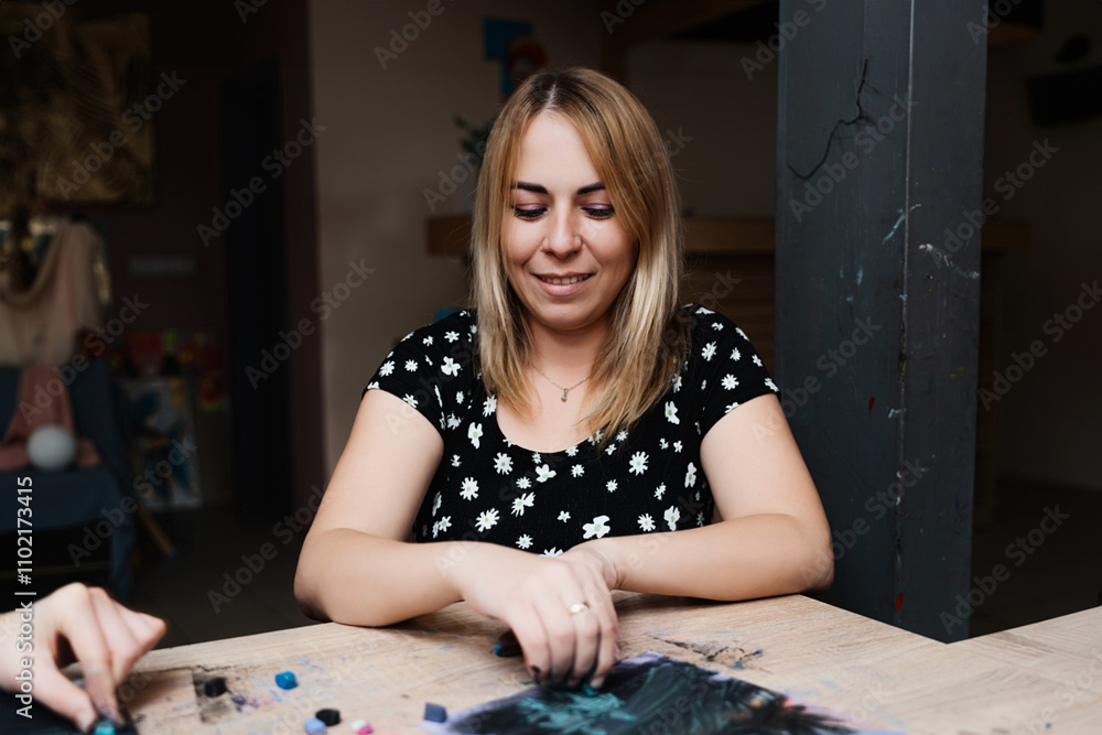 Fototapeta premium Woman creating art with pastels in a bright studio during the day