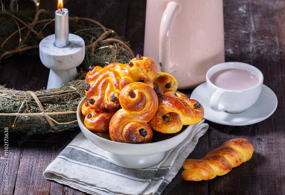 Traditional saffron Swedish buns lussekatt in different shapes, served with cocoa on a wooden table. Buns for St. Lucia's Day.