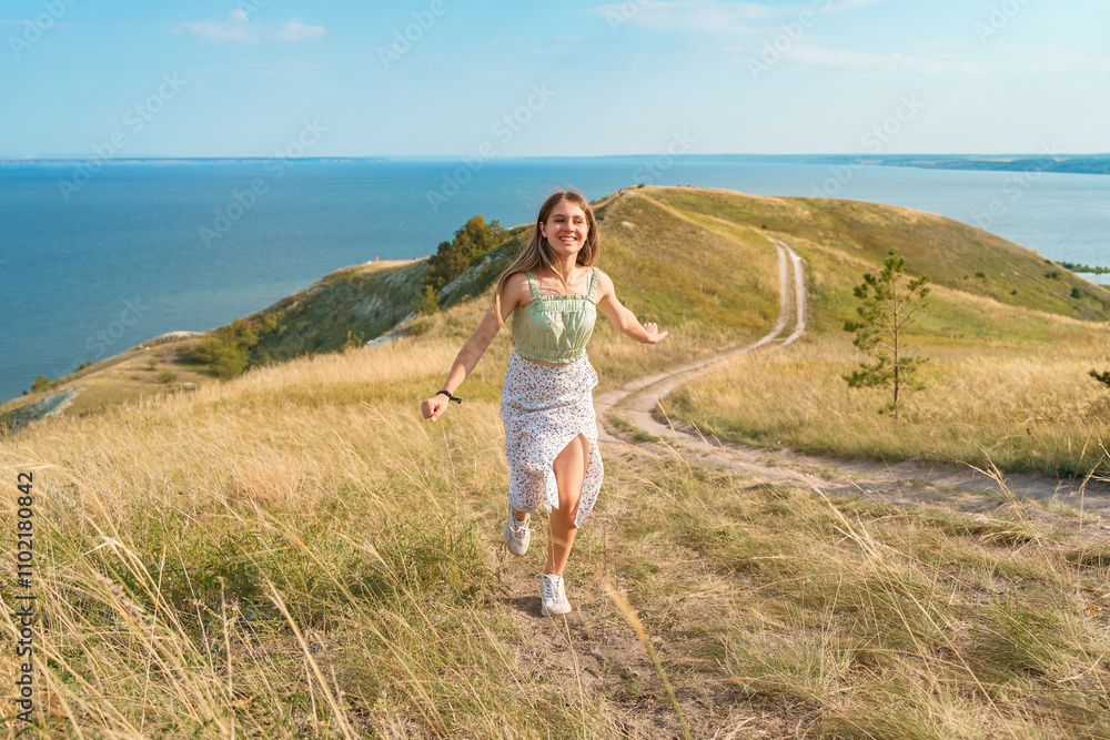 A beautiful young romantic Caucasian girl in a skirt walks along the hills and paths. Amazing view of rural scenery. nature by the river with hills and mountains. A beautiful young romantic Caucasian girl in a skirt walks along the hills and paths. Amazing view of rural scenery. nature by the river with hills and mountains.