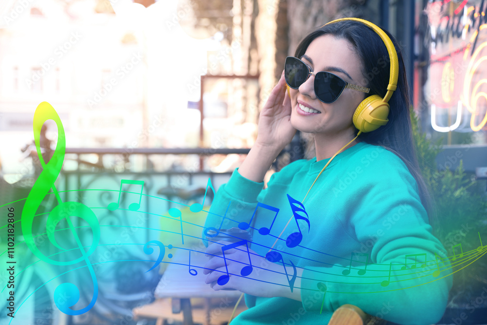 Happy young woman with coffee and headphones outdoors. Music notes flying near her Happy young woman with coffee and headphones outdoors. Music notes flying near her
