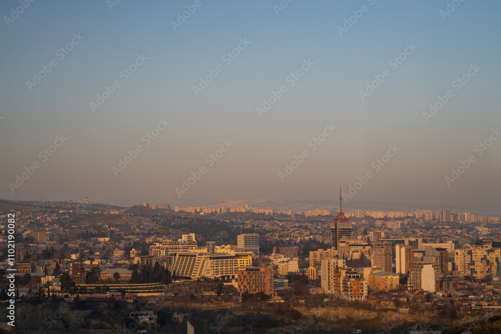 The city of Tbilisi glows softly as winter dusk descends, revealing a tranquil urban landscape embraced by nature. The city of Tbilisi glows softly as winter dusk descends, revealing a tranquil urban landscape embraced by nature.