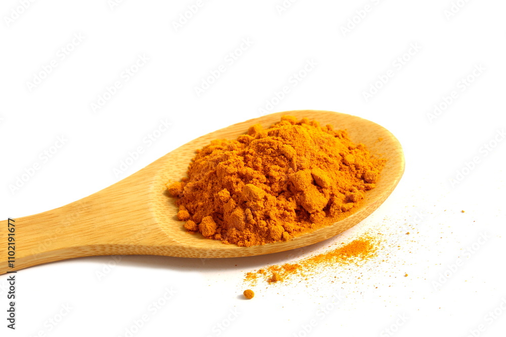 On a white background there is a wooden spoon with turmeric spice. On a white background there is a wooden spoon with turmeric spice.