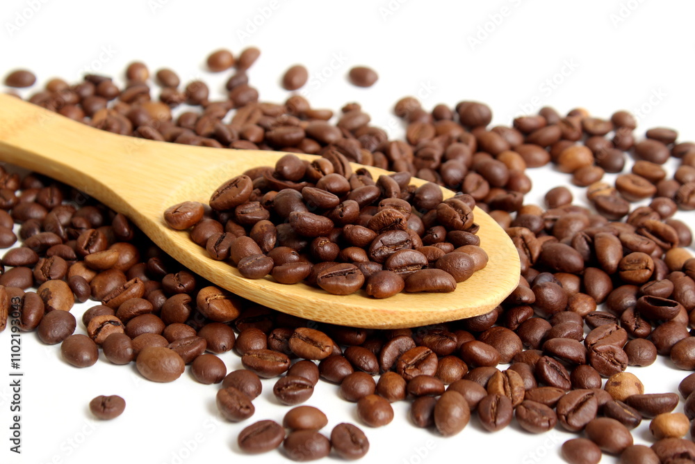 Fototapeta premium On a white background lies a wooden spoon with coffee beans. 