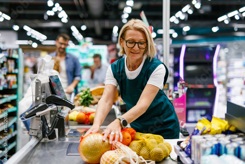 Supermarket cashier scanning groceries at checkout counter photo