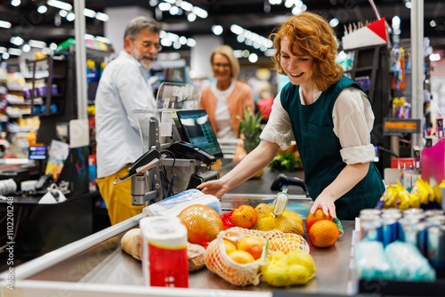 Schilderij op canvas Smiling cashier scanning groceries at supermarket checkout