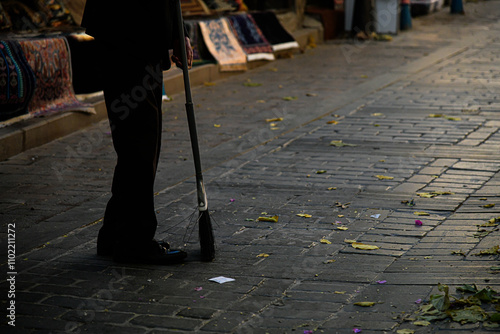Der Mann fegt die Blätter auf der Straße