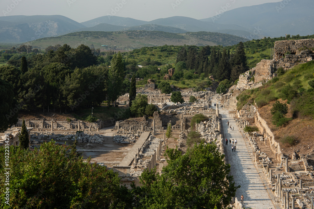 Main street in Ephesus. One of the main streets entering the ancient Greco-Roman city of Ephesus, as seen from the heights of the amphitheatre. Main street in Ephesus. One of the main streets entering the ancient Greco-Roman city of Ephesus, as seen from the heights of the amphitheatre.