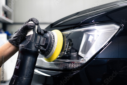 Car detailing and polishing process. Expert polishing car front lights in auto repair shop.