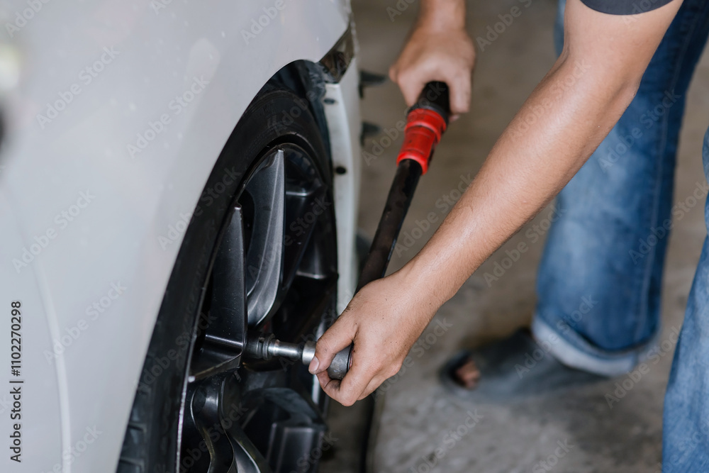 Ταπετσαρία professional mechanic is carefully tightening a car wheel nut.