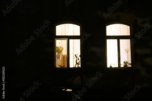 Hauswand von Jugendstilvilla mit zwei großen langen Fenstern mit Rundbogenmuster und weißem Licht in der Nacht im Winter photo