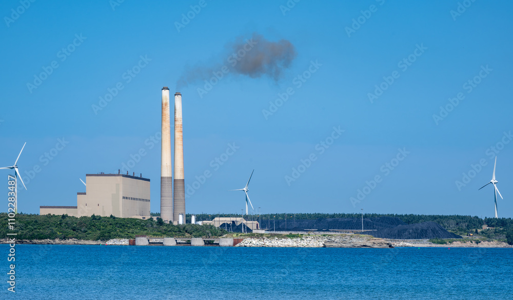 Clean and not so clean energy -A coal-fired power plant surrounded by windmill power generators Clean and not so clean energy -A coal-fired power plant surrounded by windmill power generators