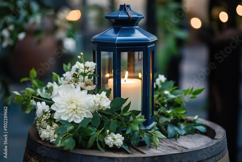 wedding centerpiece featuring a navy blue lantern with candle surrounded by lush white hydrangeas and greenery
