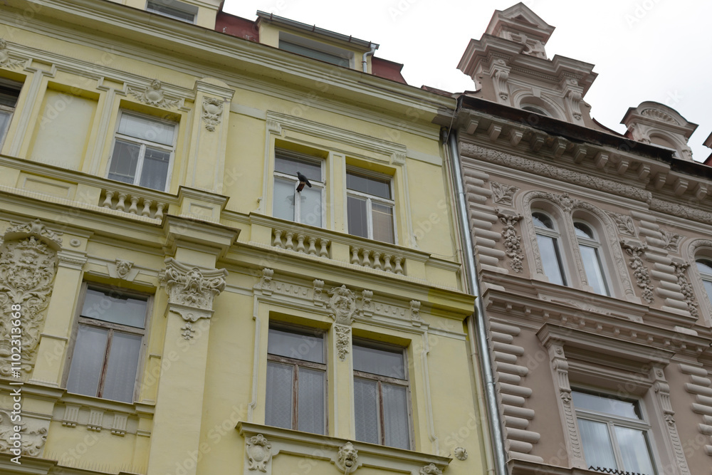 Obraz premium In the urban landscape, a vibrant yellow building stands proudly right next to an earthy brown building, adding charm to the street