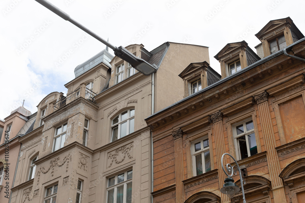 A bright street light is elegantly hanging from the roof of a tall building, illuminating the surroundings as night falls A bright street light is elegantly hanging from the roof of a tall building, illuminating the surroundings as night falls