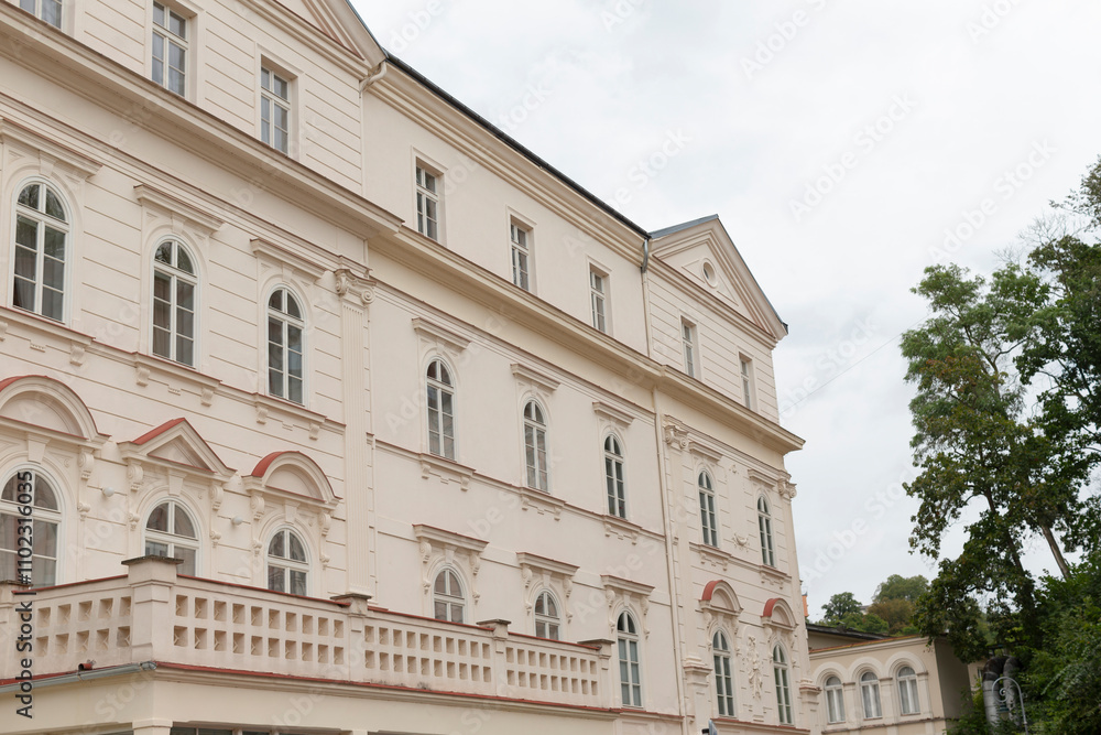 Fototapeta premium A significant and prominent large white building featuring a balcony and several trees located directly in front of it, adding to its charm