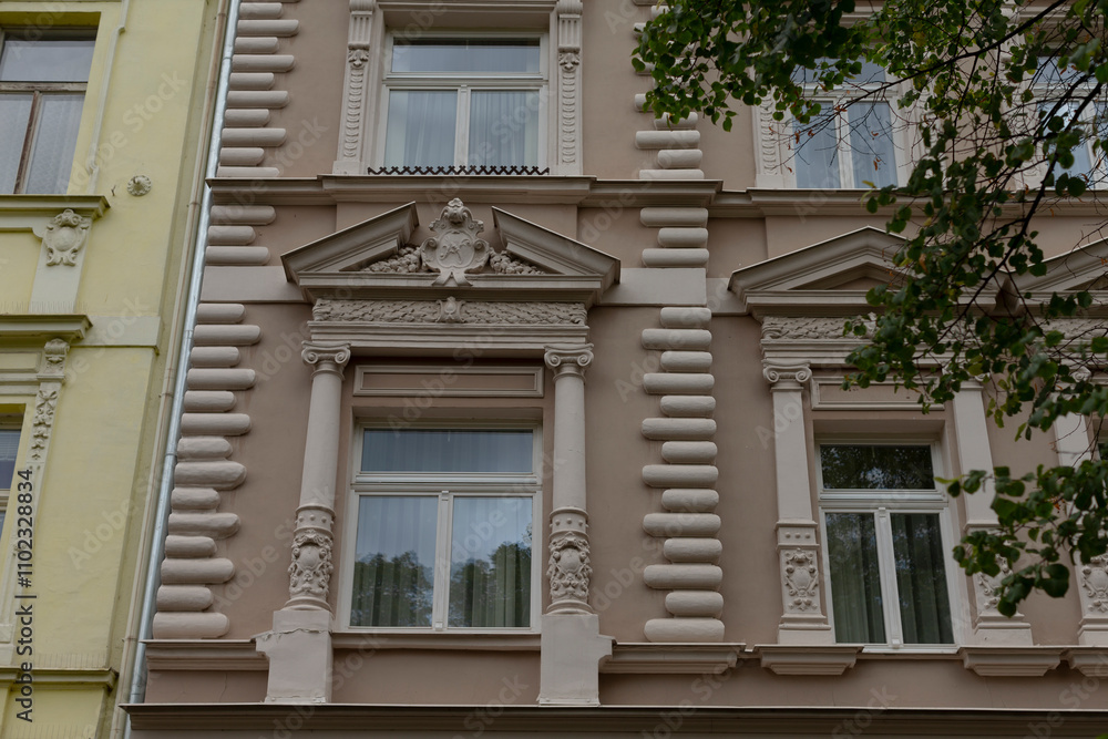 There is a prominently designed building that features numerous windows and has a beautiful tree standing gracefully in front of it There is a prominently designed building that features numerous windows and has a beautiful tree standing gracefully in front of it