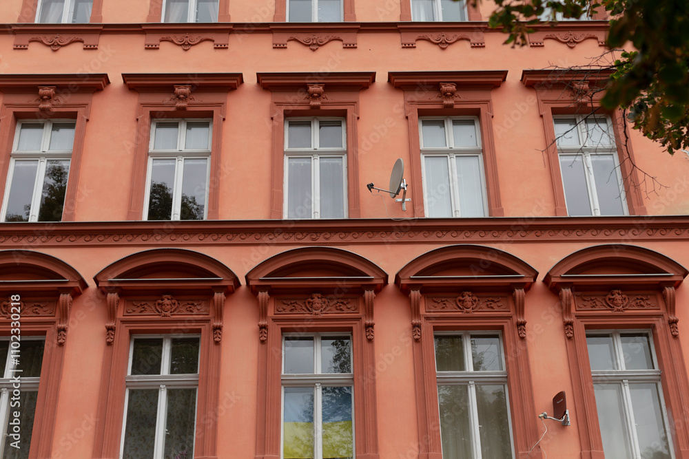 There is a very large orange building that features numerous windows, creating a bright and inviting facade that catches the eye There is a very large orange building that features numerous windows, creating a bright and inviting facade that catches the eye