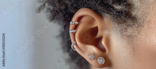 Woman showing multiple ear piercings with stylish jewelry photo